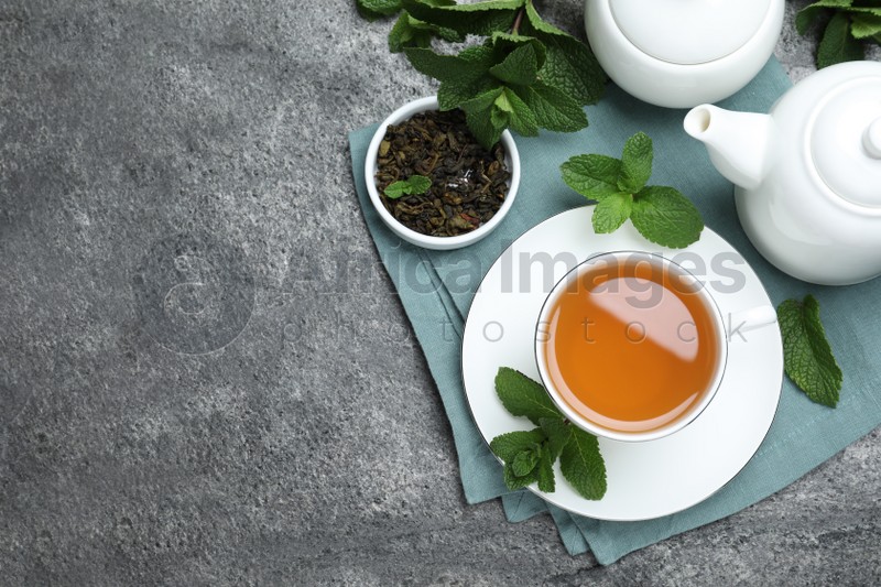 Photo of Cup of hot aromatic mint tea on grey table, flat lay. Space for text