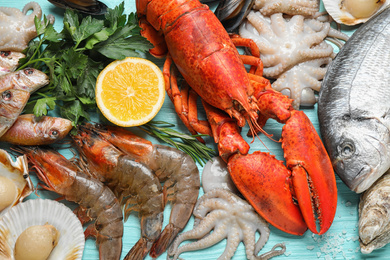 Fresh fish and different seafood on blue wooden table, flat lay
