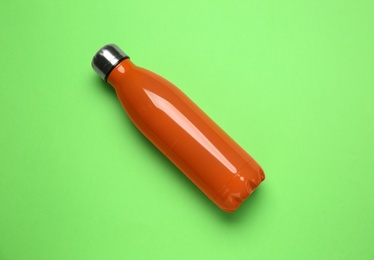 New modern thermo bottle on green background, top view