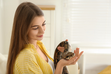 Young woman with boa constrictor at home. Exotic pet