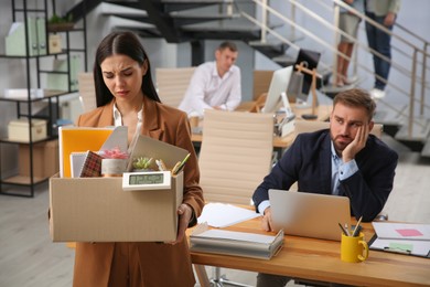 Upset dismissed young woman carrying box with stuff in office