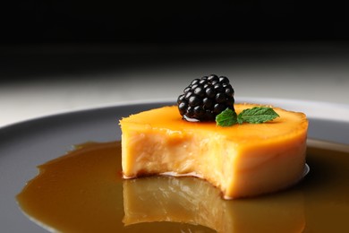 Photo of Delicious pudding with caramel and blackberry on plate, closeup