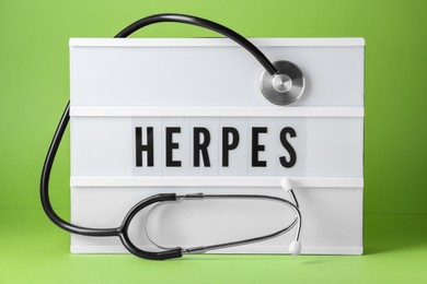 Light box with word Herpes and stethoscope on green background