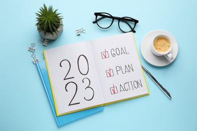 Flat lay composition of notebook with text 2023 Goal, Plan, Action on light blue background. New Year aims