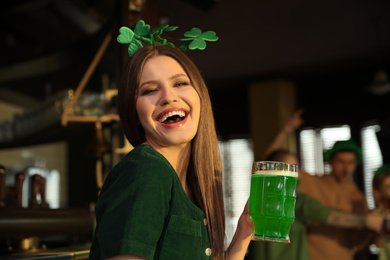 Young woman with glass of green beer in pub. St. Patrick's Day celebration
