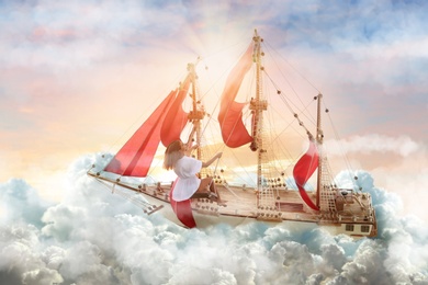 Dream world. Sailing ship with beautiful girl on board floating among wonderful fluffy clouds