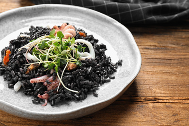 Delicious black risotto with seafood on wooden table, closeup