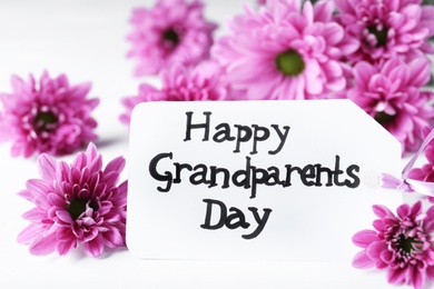 Beautiful flowers and card with phrase Happy Grandparents Day on white table, closeup