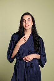 Pretty young woman in dark blue silk robe on light background