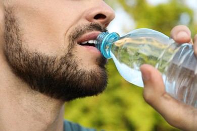 Photo of Man drinking water on hot summer day, closeup. Refreshing drink