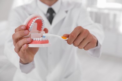 Dentist with jaws model and toothbrush in clinic, closeup. Oral care demonstration