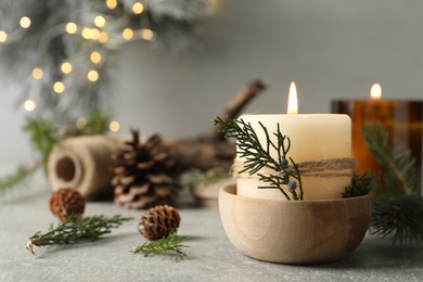 Burning candle with pinecone scent on light grey table, space for text