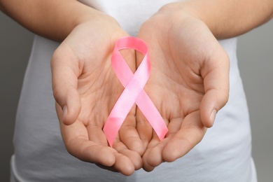 Photo of Woman holding pink ribbon, closeup. Breast cancer awareness