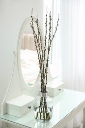 Beautiful blooming pussy willow branches on white dressing table indoors