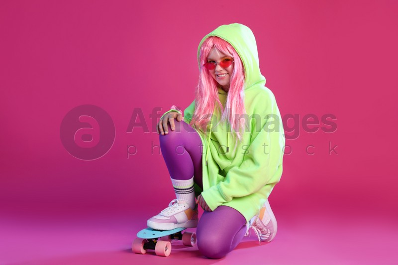 Cute indie girl with sunglasses and penny board on violet background