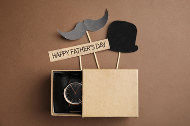 Flat lay composition with wristwatch in gift box on brown background. Happy Father;s day