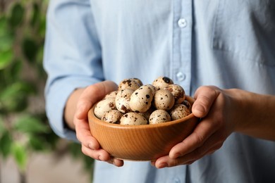 Woman with bowl of quail eggs indoors, closeup