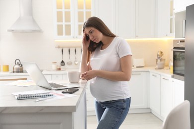 Tired pregnant woman working in kitchen at home. Maternity leave