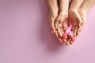 Photo of Woman and child holding pink ribbon on color background, top view with space for text. Breast cancer awareness