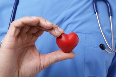 Doctor with stethoscope and red heart, closeup. Cardiology concept