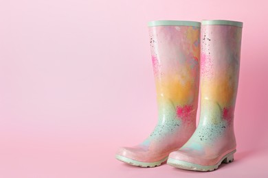 Pair of colorful rubber boots on pink background. Space for text