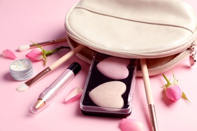 Photo of Set of makeup products with bag and roses on light pink background, closeup