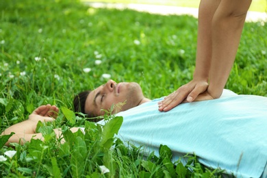 Young woman performing CPR on unconscious man outdoors, closeup. First aid