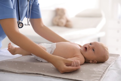 Photo of Doctor examining cute baby in clinic, closeup. Health care