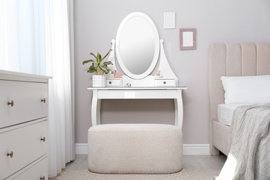 Elegant dressing table with mirror near window in bedroom