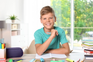 Photo of Little boy doing assignment at home. Stationery for school