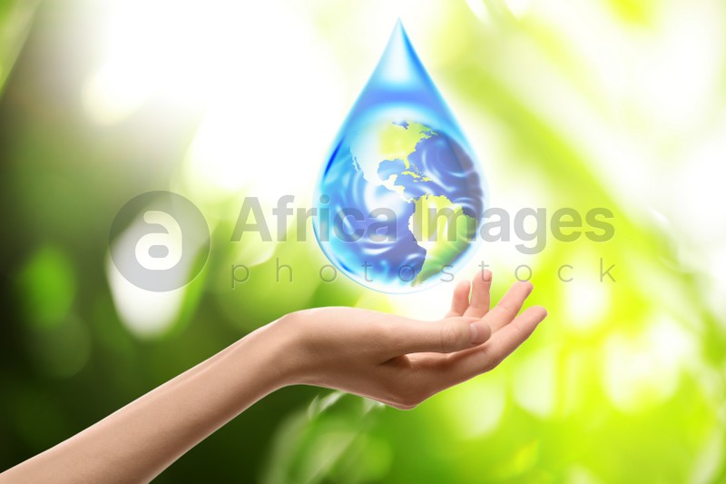 Woman holding icon of Earth in water drop on blurred green background, closeup. Ecology concept