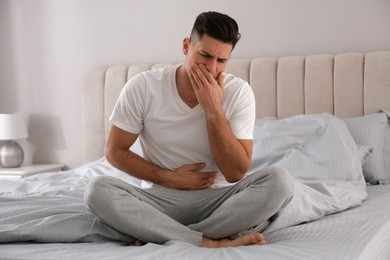 Man suffering from nausea on bed at home. Food poisoning