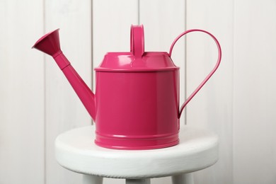 Photo of Pink metal watering can on table against white wooden background