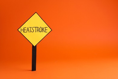 Sign with words Heat Stroke on orange background, space for text
