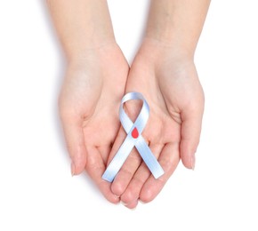 Woman holding light blue ribbon with paper blood drop on white background, top view. World Diabetes Day