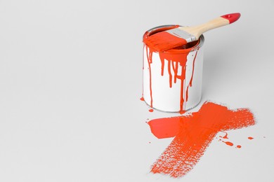 Can of orange paint and brush on white background. Space for text