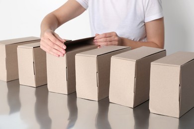 Woman folding cardboard boxes at table, closeup. Production line