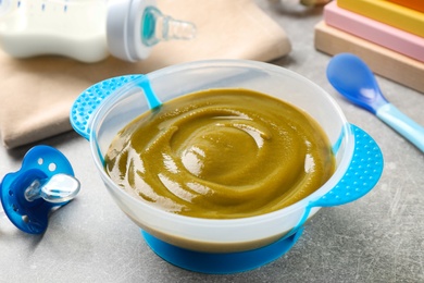 Bowl of healthy baby food on grey table