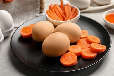 Photo of Naturally painted Easter eggs on light grey table, closeup. Carrot used for coloring