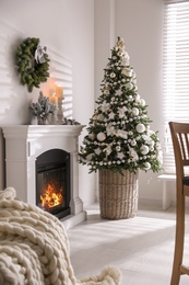 Beautiful Christmas tree and burning fireplace in living room interior