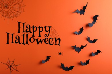 Happy Halloween. Paper bats on orange background, flat lay
