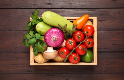 Fresh vegetables in crate on wooden table, top view