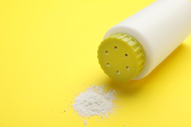Photo of Bottle and scattered dusting powder on yellow background. Baby cosmetic product