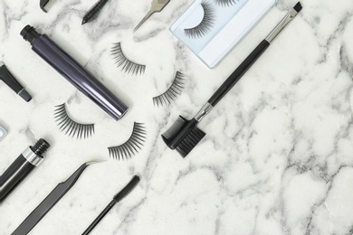 Flat lay composition with false eyelashes and cosmetic tools on light background