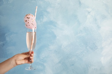 Woman holding cocktail with sweet cotton candy on blue background, closeup. Space for text