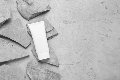 Flat lay composition with tube of hand cream and stones on grey background. Mockup for design