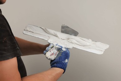 Professional worker putting plaster on putty knife indoors, closeup
