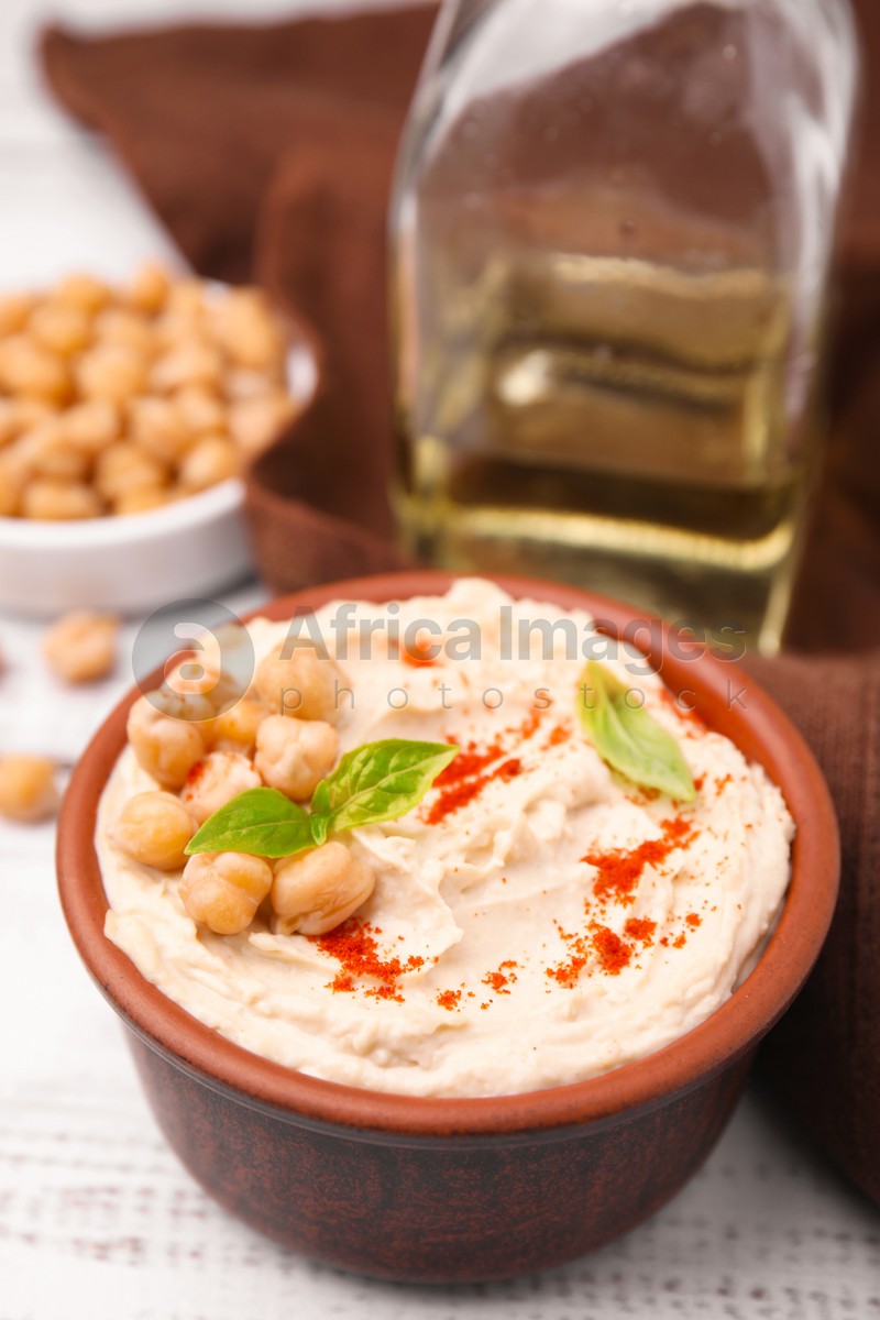 Delicious hummus with chickpeas and paprika served on white wooden table, closeup