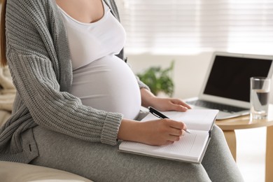 Pregnant woman working on sofa at home, closeup. Maternity leave