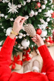Woman decorating Christmas tree at home, top view